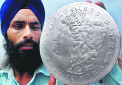  Handicraft and paper artist Gurpreet Singh shows his  creation, which is the new graphic symbol of the 1921 dollar of the United States, in Amritsar on Friday.