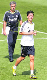 Real Madrid�s new player Mesut Ozil (R) runs past coach Jose Mourinho during their training session at the club's training grounds in Madrid on Thursday.