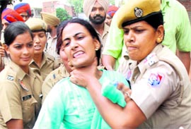 A lady police personnel grips the neck of a member of the Contract Multipurpose Health Workers Union, Punjab, during a protest by the workers outside the residence of Local Bodies Minister Manoranjan Kalia in Jalandhar on Sunday.