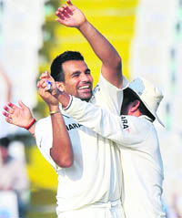 Indian cricketer Sachin Tendulkar (R) congratulates Zaheer Khan for taking the wicket of Australian batsman Michael Hussey.