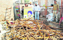 MLA Manjinder Singh Kang shows damaged hoardings carrying Manpreet Badal�s picture in Amritsar on Saturday.
