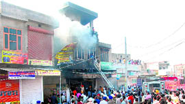 Firemen try to douse the flames in a cloth shop in Goniana (Bathinda) on Saturday.
