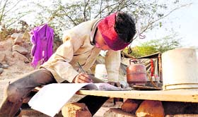 Despite scarce means, this boy is engrossed in doing his homework at a roadside stall near Gurgaon.