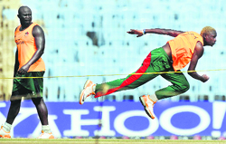 Kenyan pacer Elijah Otieno (R) bowls as Thomas Odoyo looks on during a training session at the M.A. Chidambaram Stadium in Chennai 