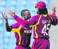 Kemar Roach (L) celebrates the wicket of Junaid Siddique with Chris Gayle in Dhaka on Friday.