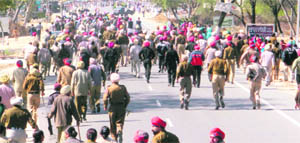 Policemen chase protesting health workers on the Fazilka-Delhi national highway at Lambi in Muktsar district on Sunday.