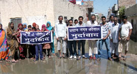 Nai Abadi residents hold demonstration against the MC and PWSSB in Abohar on Monday.