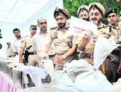 Punjab DGP PS Gill (second from R) examines a fake pistol in Chandigarh on Monday