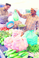 A vendor sells vegetables to a customer in a polythene bag in Patiala. 