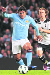 Man City's Carlos Tevez (L) runs clear of Tottenham Hotspur's Luka Modric during their EPL match in Manchester