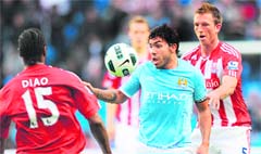 Manchester City's Carlos Tevez (C) eyes the ball under challenge from Stoke City's Danny Collins (R) and Salif Diao during their match at the City of Manchester stadium