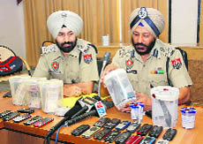 Police officers exhibit weapons, currency and other articles recovered from petrol station looters, in Bathinda on Saturday