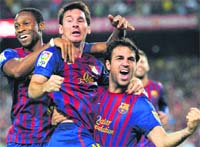 MESMERISING: Lionel Messi (C) is hugged by teammates Cesc Fabregas (R) and Seydou Keita (L) after scoring in Barcelona