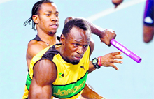 Usain Bolt (R) takes the baton from teammate Yohan Blake during the 4x100m relay final at the IAAF World Championships in Daegu on Sunday