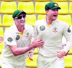 Michael Hussey (L) and Michael Clarke celebrate the fall of a Lankan wicket in Kandy on Monday.