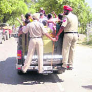 Policemen bundle up protesters into a tempo near Badal village on Monday.