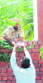 A policeman being handed over cups of tea across the police station wall. 