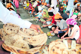 Foreign tourists sit alongside Indian devotees to eat langar at the Golden Temple in Amritsar on the occasion of the World Food Day on Sunday.