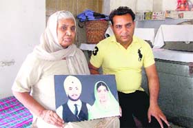 Angrej Kaur along with her son Amrik Singh shows her picture with Sarabjit Singh
