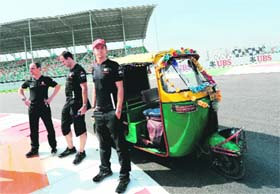 McLaren-Mercedes driver Jenson Button poses with an autorickshaw as he inspects the circuit in Greater Noida on Thursday