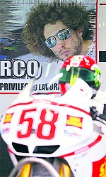 A poster of late Italian MotoGP rider Marco Simoncelli and his Honda MotoGP motorbike are displayed in tribute of him during the Valencia Grand Prix at the Ricardo Tormo racetrack in on Friday