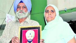 Sukhdev Singh and Sarabjeet Kaur show the picture of their son Kanwaldeep who was arrested with illegal arms in Guwahati, at their house near Patiala.