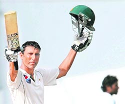 Pakistan's Younis Khan raises his bat and helmet after completing his century during the third day of the third Test against Sri Lanka in Sharjah on Saturday