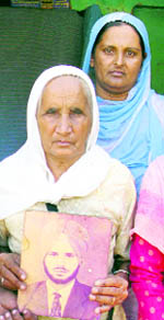 Harbans Kaur with a photograph of her husband at her house in Fiddey village of Ferozepur.