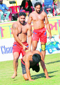 A Canadian stopper holds the leg of a raider from Nepal in Ferozepur on Saturday.