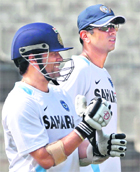 Sachin Tendulkar (L) wears his gloves as teammate Rahul Dravid looks on during a practice session in Kolkata on Sunday.