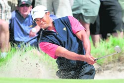 Tiger Woods hits out of a bunker in his match against Aaron Baddeley in Melbourne on Sunday. Woods defeated Baddeley to clinch the winning point for the US