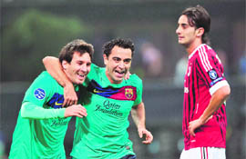 Barcelona's Lionel Messi (L) and Xavi Hernandez celebrate in front of AC Milan's Alberto Aquilani (R) during their Champions League match in Milan on Wednesday. 
