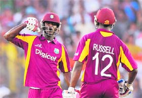 West Indies captain Darren Sammy (L) celebrates with teammate Andre Russell after hitting a boundary during the third ODI in Ahmedabad on Monday