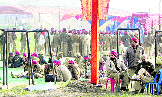 Policemen await orders at the SAD rally site in Moga�s Kili Chahal village; and (right) a giant poster of the CM and his son.