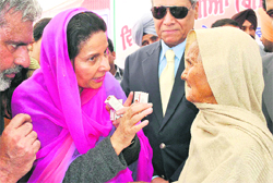 Union Minister of State for External Affairs Preneet Kaur gives medicines to an old woman at village Badshapur on Saturday. 
