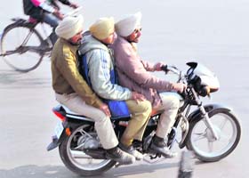 Three Punjab Police personnel ride on a motorcycle in gross violation of the traffic norms that prohibit more than two persons on a two-wheeler, at the Fountain Chowk in Patiala