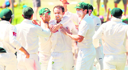 Australian teamates rush to spin bowler Nathan Lyon (C) to congratulate him for the wicket of Sachin Tendulkar at the Adelaide Oval 