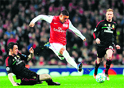 Arsenal's Alex Oxlade-Chamberlain (R) vies with AC Milan's Mark Van Bommel (L) during their UEFA Champions League match in London on Tuesday. Arsenal won the match 3-0, but lost the tie 4-3 on aggregate