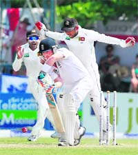 Mahela Jayawardene (L) and Prasanna Jayawardene (R) celebrate the wicket of England's Ian Bell (C) during the second day of the first Test in Galle on Tuesday