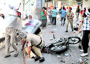The security guard of Patiala SSP Gurpreet Singh Gill (on the floor) shields him from a stone-pelting mob at Arya Samaj Chowk in Patiala