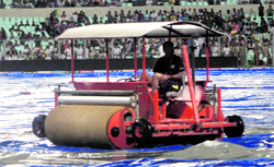 A groundsman uses a super sopper at Eden Gardens to remove water from the field after rain in Kolkata on Tuesday evening.