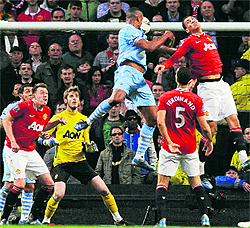 Manchester City's Vincent Kompany (C) heads and scores during their match against Manchester United at the Etihad stadium in Manchester on Monday. City won 1-0 and are now level on points with United, but ahead on goal difference