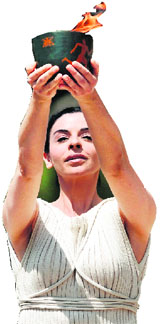 Actress Ino Menegaki, acting as high priestess holds an urn carrying the Olympic Flame during the lighting ceremony in ancient Olympia. The Olympic flame was lit in a solemn ceremony filled with mystery and tradition that signals the final countdown to the start of this year's summer Games in London. 