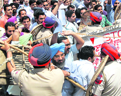 Policemen try to control contractual Sarva Shiksha Abhiyan teachers who were protesting outside the residence of Local Bodies Minister Bhagat Chunni Lal demanding regular jobs, in Jalandhar on Saturday.