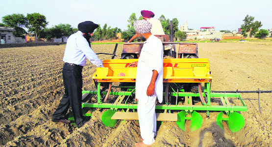 An expert explains the trench method for maize farming to a farmer in a Moga village.