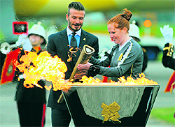 Former England footballer David Beckham (L) lights the Olympic torch after its arrival at RNAS Culdrose air base in Cornwall, south-west England