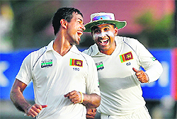 Sri Lanka's Nuwan Kulasekara (L) celebrates with Mahela Jayawardene after taking the wicket of Pakistan's Taufeeq Umar during the third day of their first Test in Galle. 
