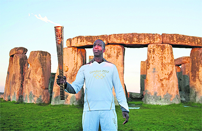 Former U.S. athlete Michael Johnson holds the Olympic Torch at Stonehenge, a World Heritage site, in Salisbury, southern England, on Thursday. 