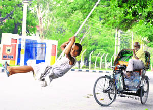 A girl uses a swing tied to a tree in Patiala on Friday