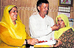 Vijay Kumar's family members celebrate with sweets after he won a silver medal in shooting on Friday